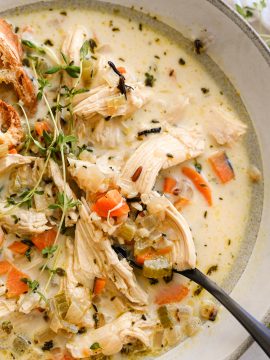 A bowl of creamy chicken and wild rice soup with carrots, celery, and tender shredded chicken in a thick, cozy broth.