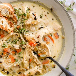 A bowl of creamy chicken and wild rice soup with carrots, celery, and tender shredded chicken in a thick, cozy broth.