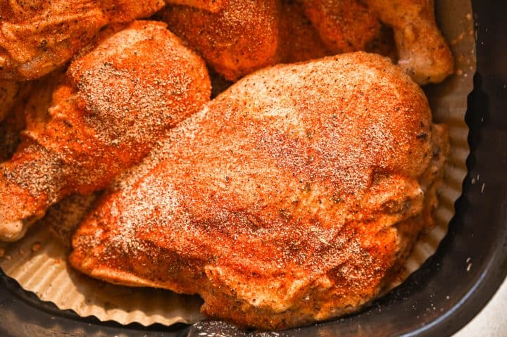 Fresh raw chicken breasts coated with seasoned herbs ready for cooking.