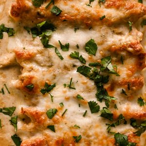 Green Chile Chicken Enchiladas with cheese and fresh herbs.